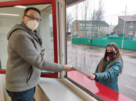 Die Schülerin Sophie Rönning erhält vom kommissarischen Schulleiter Axel Krämer ihre Lernmaterialien fürs "Home Office" durchs Fenster gereicht. Bild: Röttgers 